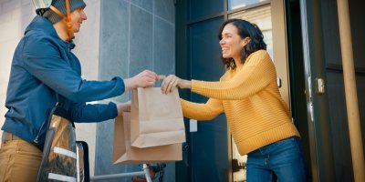 Kurýr doručuje zboží v papírových taškách zákaznici