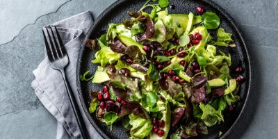 Salát na černém talíři, vedle vidlička a utěrka