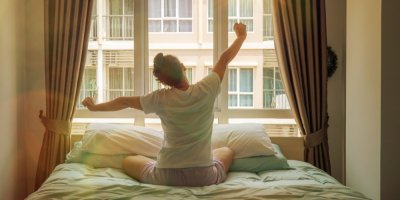 Žena se protahuje na posteli po probuzení