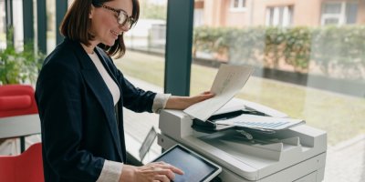 Žena tiskne dokumenty v moderní kanceláři