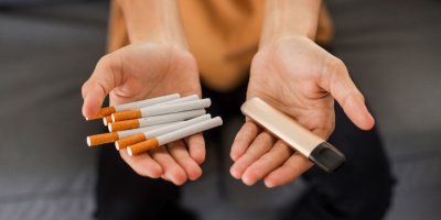 Cigarety a elektronická cigareta v dlaních