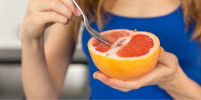 Žena v modrém tričku jí grapefruit