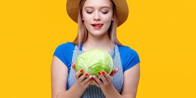 Mladá farmářka drží v rukou zelí a olizuje si ret