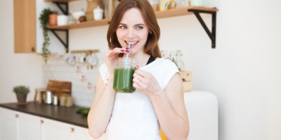 Mladá žena pije zelený nápoj