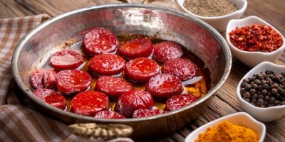 Smažená kolečka turecké klobásy sucuk, koření v miskách