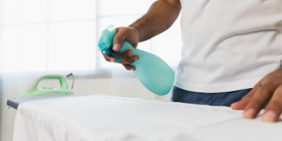 Muž sprejuje oblečení na žehlicím prkně