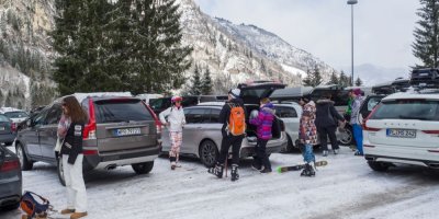 Lyžaři u aut na parkovišti v lyžařském středisku v Rakousku