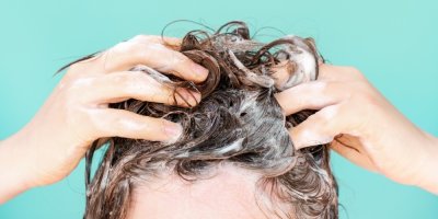 Žena si myje vlasy šamponem