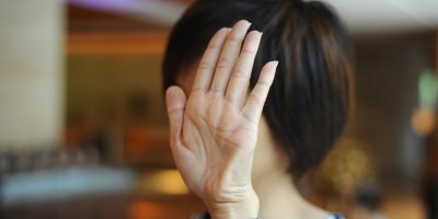 Žena si zakrývá rukou obličej