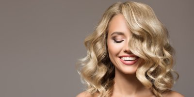 Žena s blonďatými vlnitými vlasy se usmívá