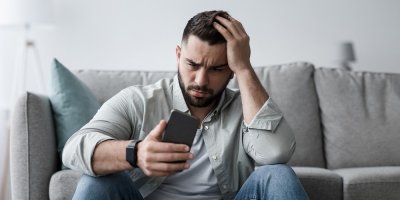 Frustrovaný muž se dívá do telefonu