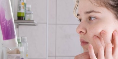 Smutná dívka se dívá v koupelně do zrcadla