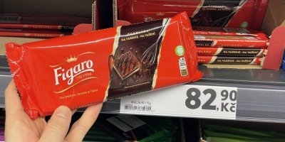 Ruka držící tabulkovou čokoládu před regálem supermarketu