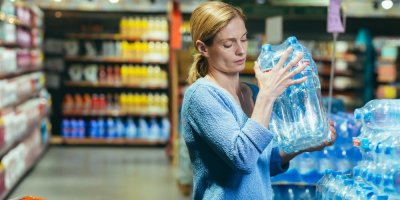 Žena v supermarketu nakupuje balené minerální vody