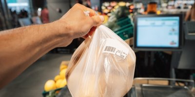 Ruka držící sáček brambor u váhoskeneru v supermarketu