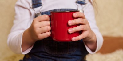Červený hrnek v rukou dítěte