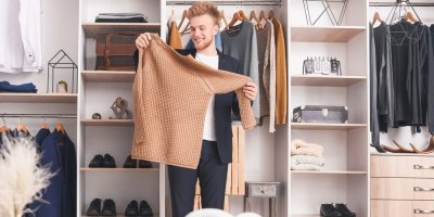 Muž drží svetr před skříní