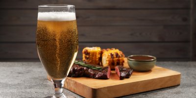 Pivo ve skleničce, v pozadí jídlo