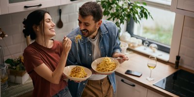 Žena a muž jí špagety v kuchyni