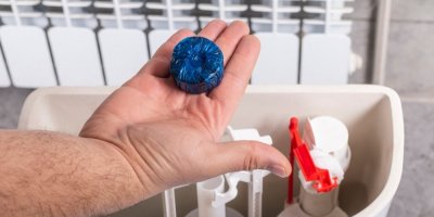 Ruka držící tabletu do toaletní nádržky