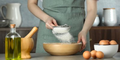 Žena prosívá mouku do misky