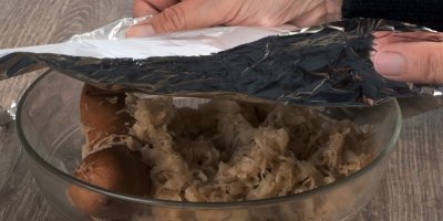 Kuchařka přikrývá pokrm v misce alobalem