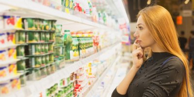 Žena v obchodě vybírá produkty z regálu ve výši očí