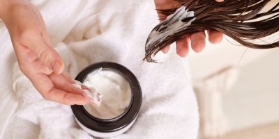 Žena si aplikuje masku na vlasy