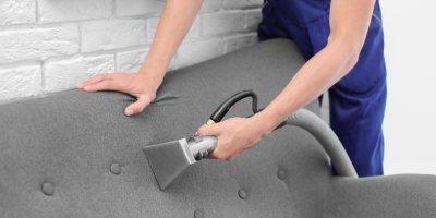 Člověk čistí sedačku parním čističem