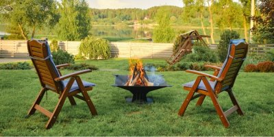 Ohniště a dvě dřevěné židle na zahradě s výhledem na rybník