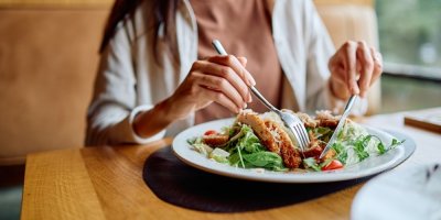 Žena jí zeleninový salát s kousky masa