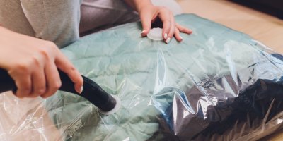 Žena vysává vzduch z vakuového pytle, ve kterém jsou zimní bundy