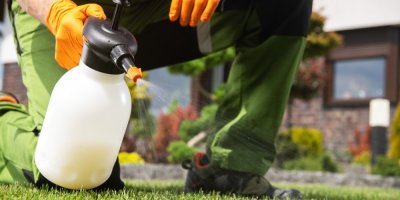 Muž stříká na trávu z postřiku