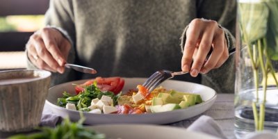 Žena jí zeleninové jídlo z keramického talíře.