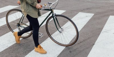 Žena kráčí přes přechod a vede s sebou jízdní kolo 