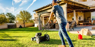 Muž se sekačkou před domem