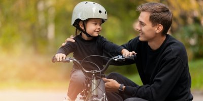 Otec učí malou dceru jezdit na kole