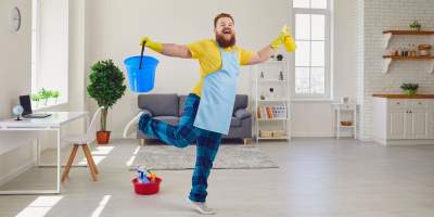 Muž má gumové rukavice a zástěru, v ruce drží čisticí prostředek