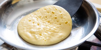 Člověk obrací lívanec na pánvi