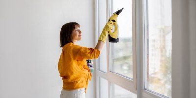 Žena utírá okno elektrickou stěrkou