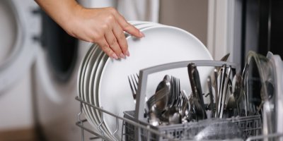 Žena vytahuje čisté nádobí z myčky