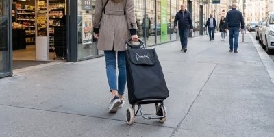 Mladá žena jde s taškou po ulici 