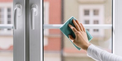 Ženská ruka čistí okno hadříkem