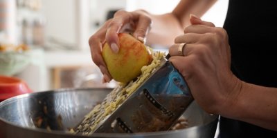 Žena na struhadle strouhá jablko.