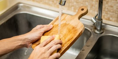 Člověk umývá dřevěné prkénko na krájení