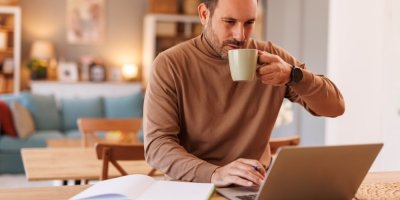 Muž pije kávu u notebooku