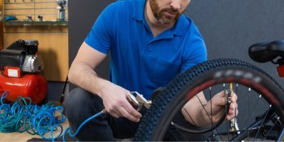 Muž nafukuje pneumatiku horského kola kompresorem