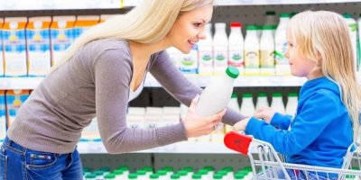 Mladá žena a její malá dcera sedící v nákupním vozíku spolu nakupují v supermarketu