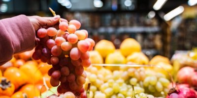 Žena drží trs hroznového vína v supermarketu