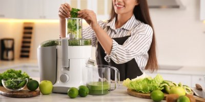 Žena dává zeleninu a ovoce do odšťavňovače